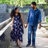 Indian couple posing for maternity baby shoot. The couple is posing in a lawn with green grass and the woman is falunting her baby bump in Lodhi Garden in New Delhi, India photo