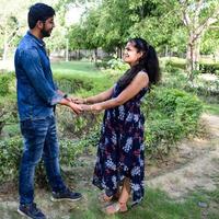 pareja india posando para una sesión de fotos de maternidad. la pareja está posando en un césped con hierba verde y la mujer está faluntando su panza en el jardín lodhi en nueva delhi, india