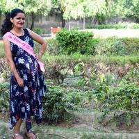 Indian couple posing for maternity baby shoot. The couple is posing in a lawn with green grass and the woman is falunting her baby bump in Lodhi Garden in New Delhi, India photo