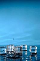 cubos de hielo en agua azul brillante y un toque de gotas de lluvia.