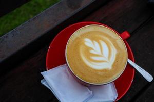 cup of cappuccino with latte art on wooden background. photo