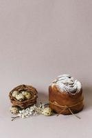 Pie, a traditional Orthodox Easter cakes, quail eggs in a bird's nest and flowers on a beige background. Festive Easter Card photo