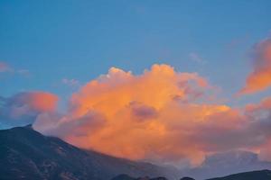 Sunset in the mountains, the clouds over the mountain are illuminated by the setting sun, the idea for the background, the weather wallpaper, the beautiful nature of the mountains photo