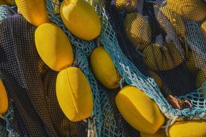 Pile of multi-colored fishing nets with yellow floats dry on the pier, close-up, selective focus. Background to the concept of traditional fishing in coastal towns photo