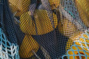 Fishing net with yellow floats dries on the pier, close-up, selective focus. concepts of fishing in coastal towns photo