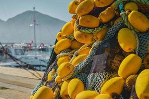 Bunch of tangled multi-colored fishing nets with yellow floats on the background of the marina, close-up, selective focus. Background for the concept of traditional fishing in coastal towns photo