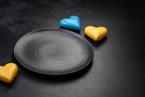 corazones de chocolate con los colores de la bandera ucraniana en un plato de cerámica negra foto