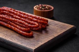 Delicious thin smoked meat sausages with spices and herbs photo