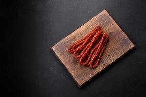 Delicious thin smoked meat sausages with spices and herbs photo