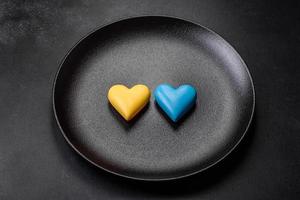 Chocolate hearts in the colors of the Ukrainian flag on a black ceramic plate photo