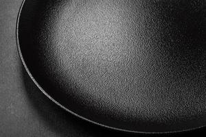 Empty beautiful black ceramic plate on a dark concrete background photo