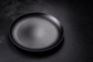 Empty beautiful black ceramic plate on a dark concrete background photo