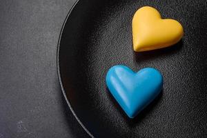 corazones de chocolate con los colores de la bandera ucraniana en un plato de cerámica negra foto