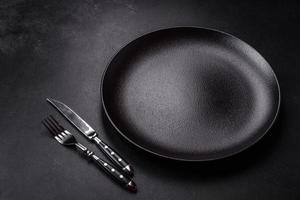 Empty beautiful black ceramic plate on a dark concrete background photo