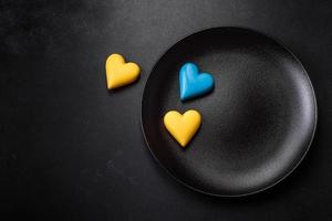 Chocolate hearts in the colors of the Ukrainian flag on a black ceramic plate photo