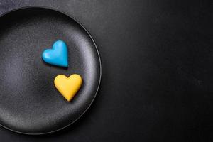 Chocolate hearts in the colors of the Ukrainian flag on a black ceramic plate photo