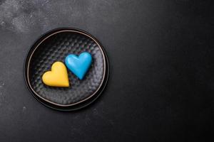 Chocolate hearts in the colors of the Ukrainian flag on a black ceramic plate photo