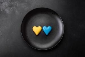 Chocolate hearts in the colors of the Ukrainian flag on a black ceramic plate photo