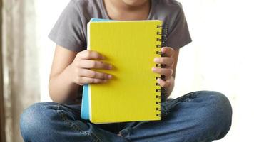 Boy Sitting On The Floor And Holding A Stack Of Notebooks video