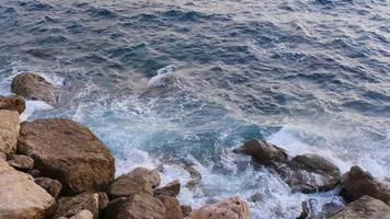 olas del océano rompiendo y fluyendo en las rocas de la costa, imágenes de la naturaleza 4k. video