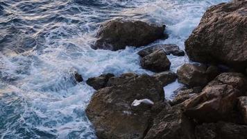 ondas do mar quebrando nas rochas no litoral e as gaivotas voando perto, imagens da natureza 4k. video