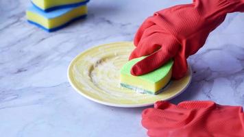 hombre con guantes protectores de goma sosteniendo una esponja limpiando un plato colorido video