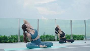 Due Asia sottile donna praticante yoga su il balcone di sua condominio. asiatico donna fare esercizi nel mattina. equilibrio, meditazione, rilassamento, calma, bene Salute, felice, relax, salutare stile di vita concetto video