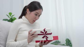 jolie femme asiatique se sent surprise et regarde l'intérêt à l'intérieur de la boîte de cadeaux. jolie fille excitée coffret cadeau ouvert. anniversaire, fête, Noël, Festival du nouvel An, remercier, célébrer, la Saint-Valentin, anniversaire video