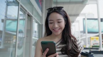 Modern happy asian Female lifestyle fashion portrait. beautiful attractive young woman girl enjoy stylish walk with shopping bag packages use smartphone on the street, trendy outfit on shopping mall video