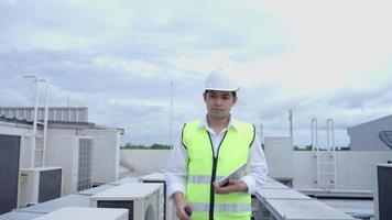 Asian maintenanc e engineer works on the roof of factory. contractor  inspect compressor system and plans installation of air condition systems in construction site of modern buildings. video