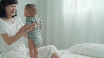 concept learning development in baby. A mother is training her 8-month to stand to improve walking. A mother hug baby after baby can stand development. video