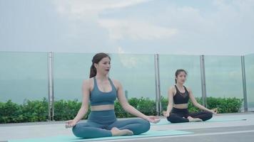 mujer delgada practicando yoga en el balcón de su condominio. mujer asiática haciendo ejercicios por la mañana. equilibrio, meditación, relajación, calma, buena salud, feliz, relax, concepto de estilo de vida saludable video