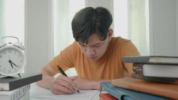 el estudiante asiático tiene ansiedad debido a los exámenes, los hombres se preparan para el examen y aprenden lecciones en la biblioteca. estrés, desesperación, prisa, lectura incomprensible, desánimo, expectativa, conocimiento. video