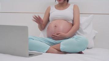 Pregnant woman taking a video conference with her husband. A pregnant woman and husband bought pink shoe for daughter . Family concept.