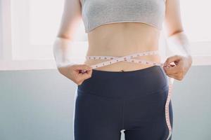 hermosa mujer gorda con cinta métrica usa su mano para exprimir el exceso de grasa que está aislado en un fondo blanco. ella quiere perder peso, el concepto de cirugía y descomponer grasa bajo el foto