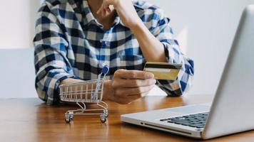 manos sosteniendo la tarjeta de crédito y usando la computadora portátil. las compras en línea foto