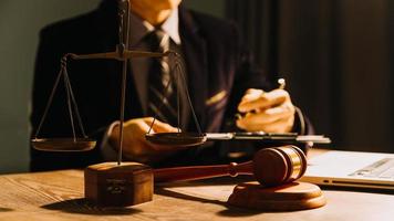 Business and lawyers discussing contract papers with brass scale on desk in office. Law, legal services, advice, justice and law concept picture with film grain effect photo