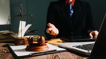 Business and lawyers discussing contract papers with brass scale on desk in office. Law, legal services, advice, justice and law concept picture with film grain effect photo