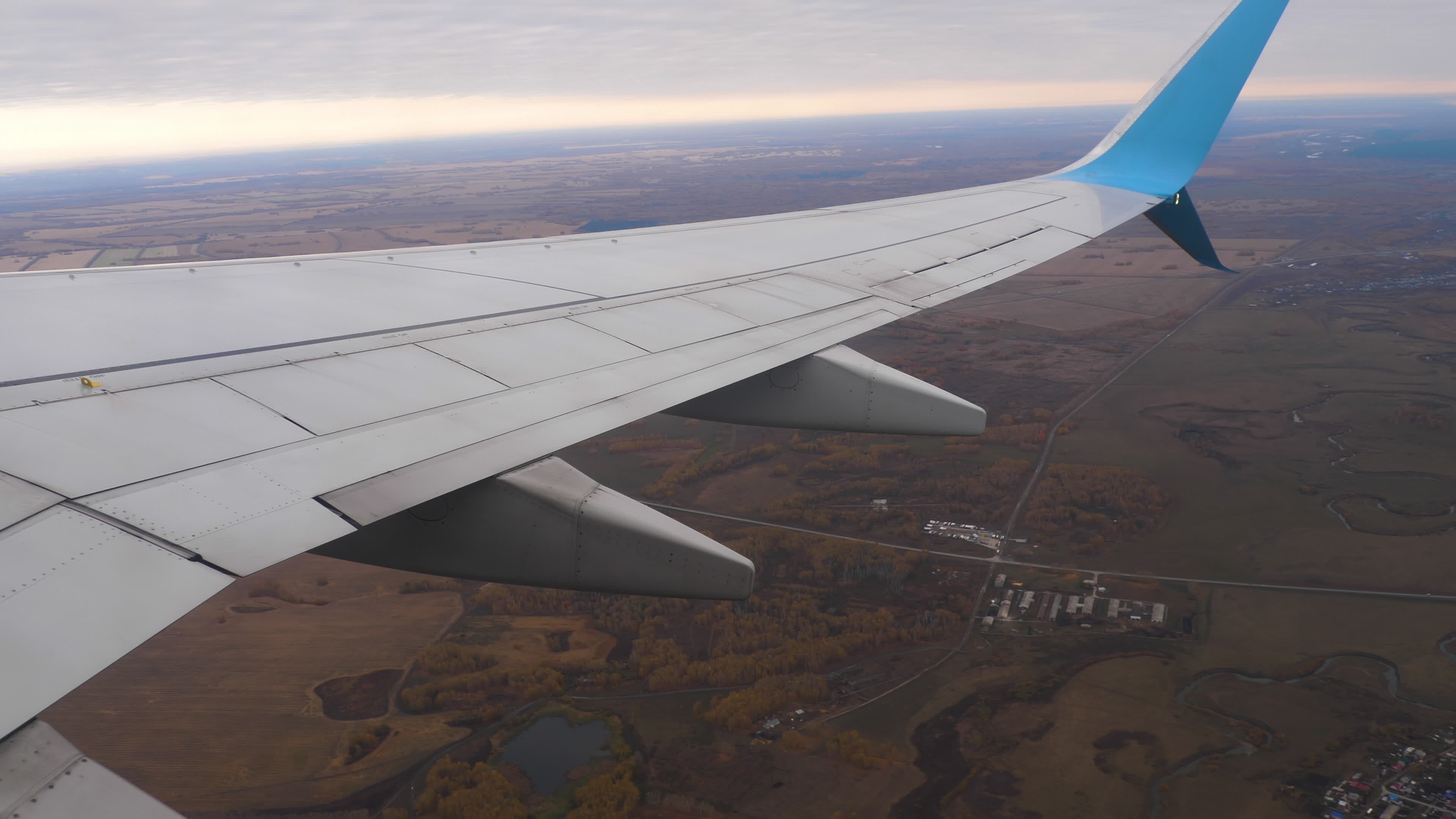 View from the porthole on the wing, flight. Fly over beautiful fields