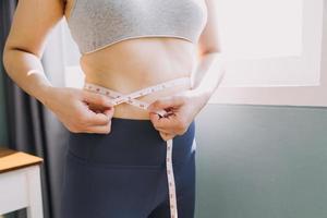 hermosa mujer gorda con cinta métrica usa su mano para exprimir el exceso de grasa que está aislado en un fondo blanco. ella quiere perder peso, el concepto de cirugía y descomponer grasa bajo el foto