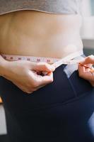 Beautiful fat woman with tape measure She uses her hand to squeeze the excess fat that is isolated on a white background. She wants to lose weight, the concept of surgery and break down fat under the photo