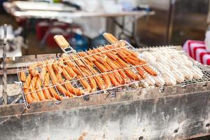 Fresh sausage and hot dogs grilling outdoors on a gas barbecue grill. photo