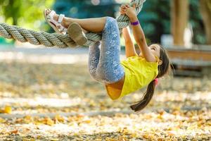 Charming little girl climbs on rope photo