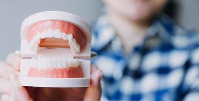 Stomatology concept, partial portrait of girl with strong white teeth looking at camera and smiling, fingers near face. Closeup of young woman at dentist's, studio, indoors photo