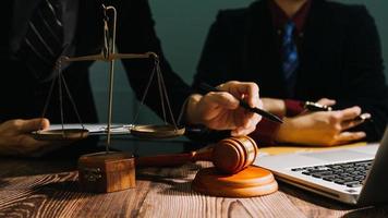 Business and lawyers discussing contract papers with brass scale on desk in office. Law, legal services, advice, justice and law concept picture with film grain effect photo