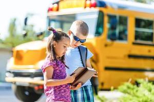 riendo sonriente niño caucásico estudiante niño con expresión de cara divertida caminando cerca del autobús amarillo el 1 de septiembre. educación y concepto de regreso a la escuela. niño alumno listo para aprender y estudiar. foto