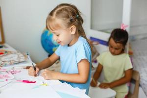 education, creation and school concept - smiling little student girl drawing and daydreaming at school photo