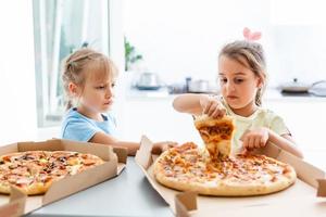 Two little girls eating pizza photo