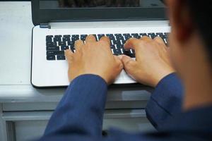 picture of an Asian business man hands working in office with laptop computer, typing on keyboard at his desk, close up photo