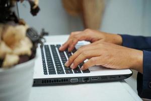 picture of an Asian business man hands working in office with laptop computer, typing on keyboard at his desk, close up photo